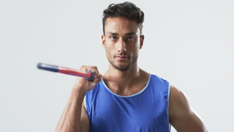 young biracial athlete man holding a javelin in a studio setting on a white background