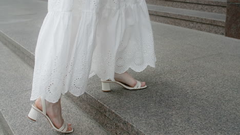 woman walking up stairs in a white dress and white heels