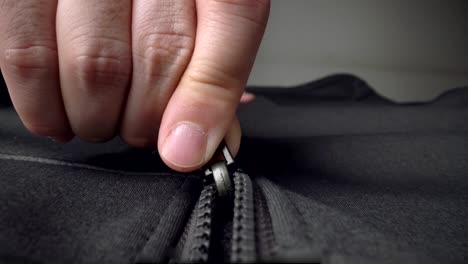 extreme close up zipper with hand unzipping the sweater jacket zipper.