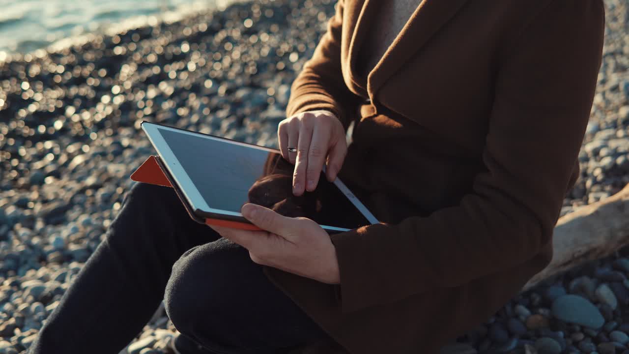 женщина использует планшет на пляже
