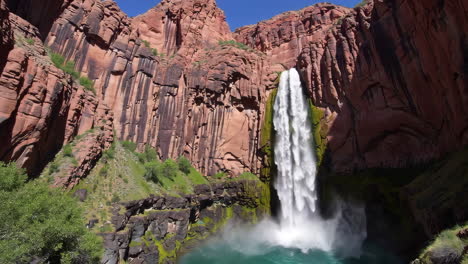 majestic waterfall plunging into a turquoise pool amidst red rock cliffs