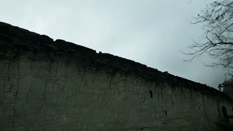 a stone wall with an overcast sky and trees