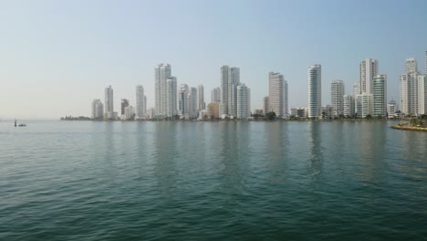 drone flies above people on fishing boat, cartagena skyline in background