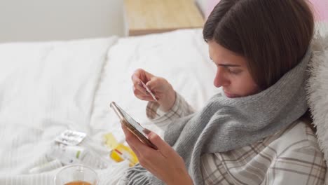 sick-girl-lying-in-bed-reads-on-the-Internet-about-self-medication-and-drinks-tea