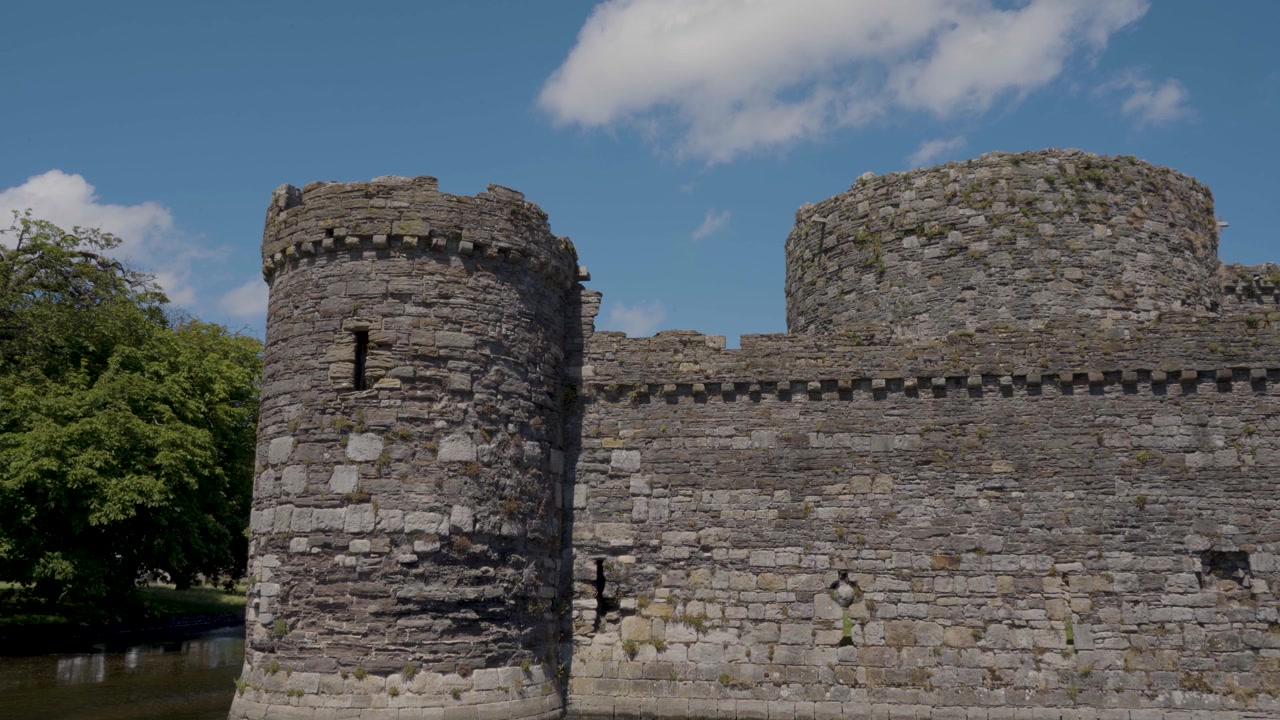Composizione statica delle imponenti mura in pietra del Castello di Beaumaris, con muratura dettagliata e antiche torri che creano una ricca rappresentazione visiva di una delle più importanti fortificazioni medievali del Galles.
