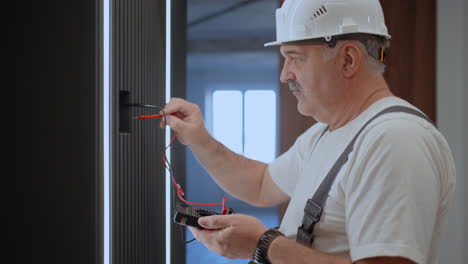 hombre electricista comprueba el voltaje en la red con un probador de alambre preparándose para instalar un hogar inteligente