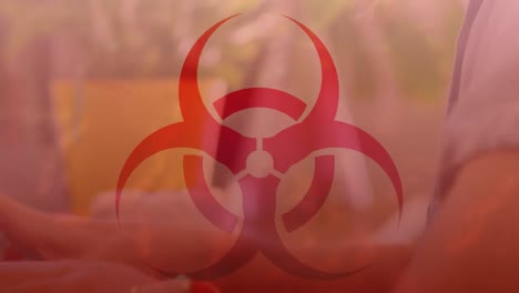 animation of biohazard symbol over caucasian businesswoman using laptop in office