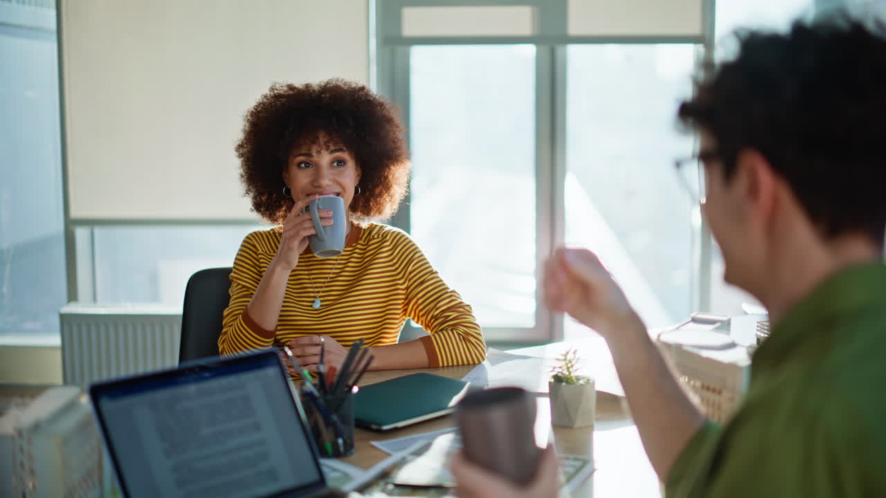 Smiling colleagues clinking cups taking break at construction office closeup