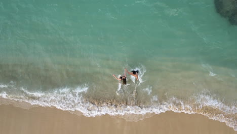 couple running while holding hands on the lanikai beach at kailua, hawaii