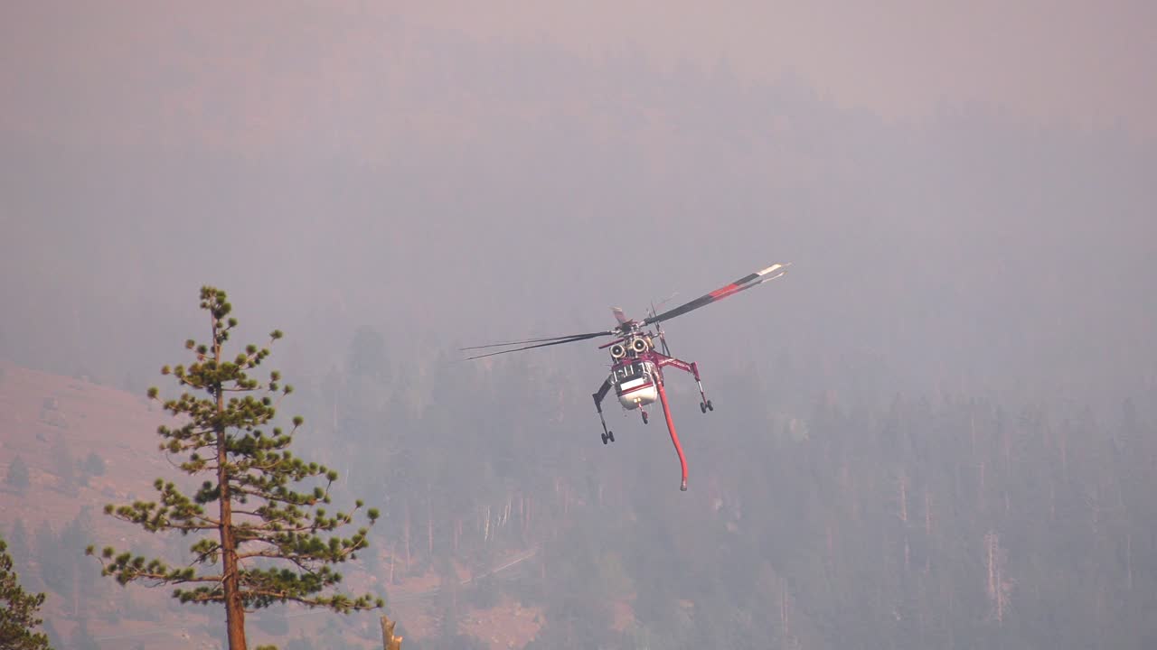 helicóptero de bombero volando sobre un lago, mientras lucha contra incendios forestales, en el oeste de estados unidos - cámara lenta, alejar el tiro