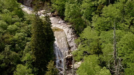 drone flies above white water rapids surging near a waterfall hidden in dense smoky mountain forest