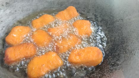 chicken nuggets deep frying in a wok