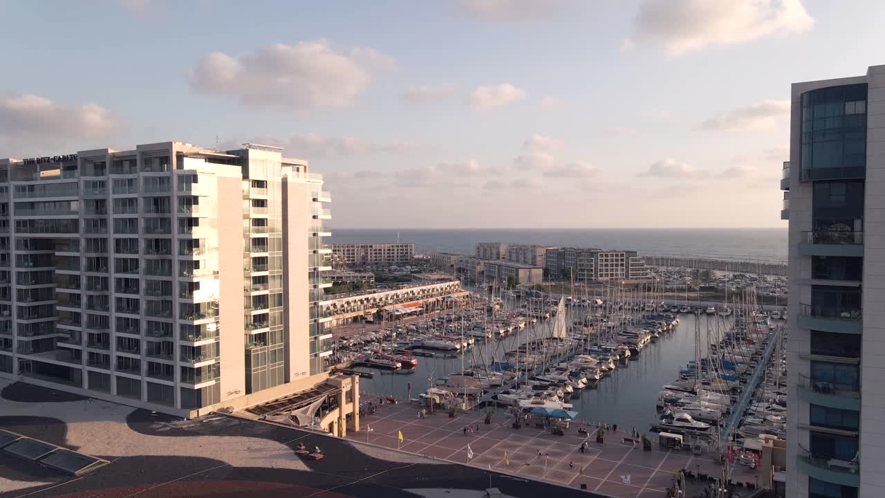 Aerial view of the harbor with boats and tall buildings in Herzelia in summer at sunset