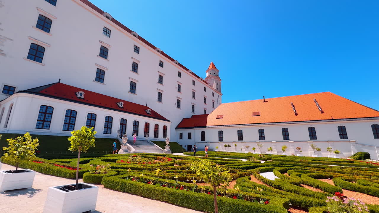 Bratislava, Slovakia, 2 June 2025: Walk along the beautiful garden at the façade of the Bratislava Castle in Slovakia. Few people walk by the lovely territory taking pictures