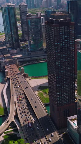 chicago harbor yacht club with numerous boats on water. busy motorway going through lake bank. skyscrapers towering over the sea-green waters. vertical video