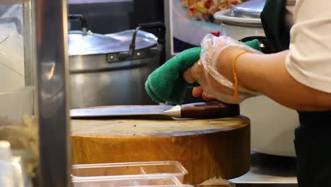 person meticulously sharpening a knife on a board.