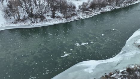 static view of ice floating down a river surrounded by snow