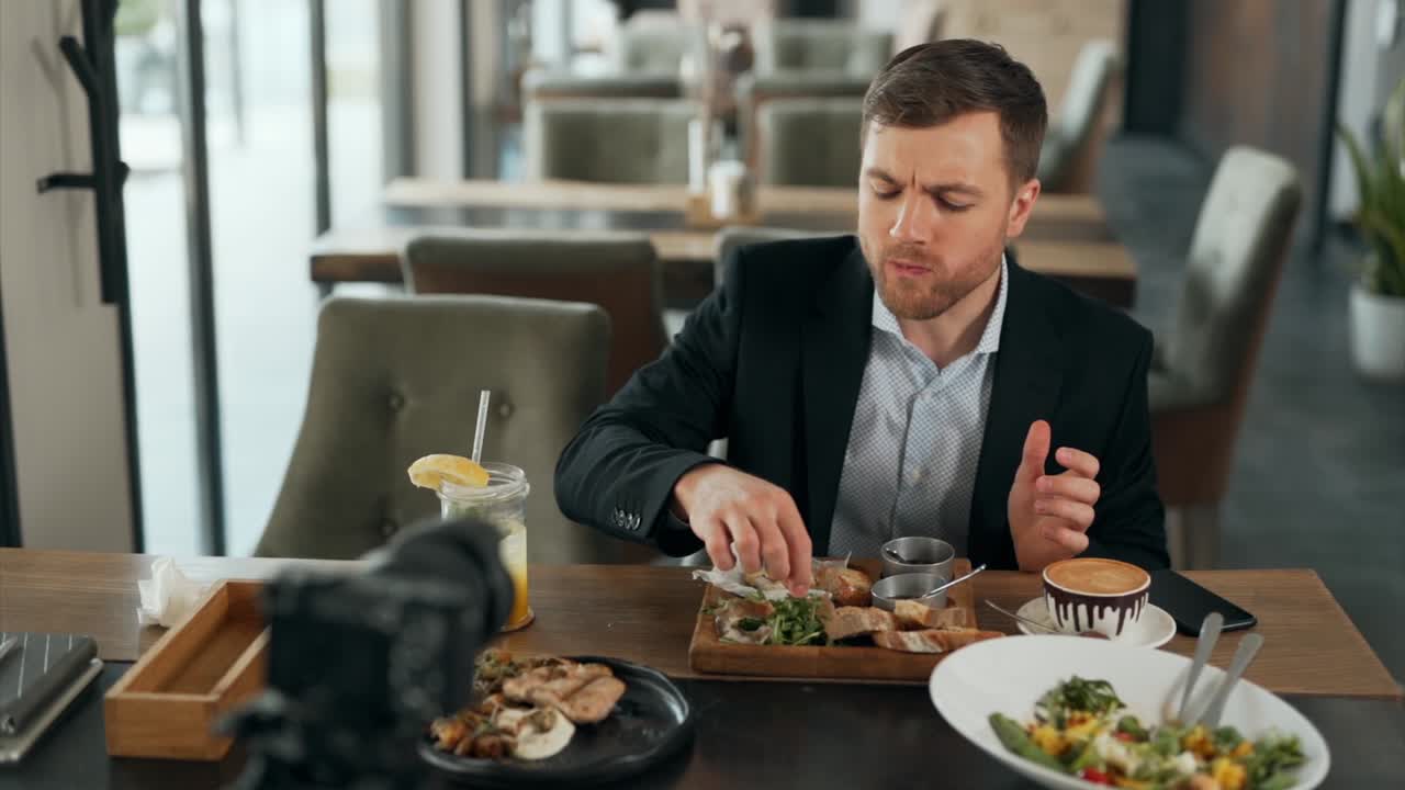 Handsome young man evaluates the dishes in the restaurant and shoots everything on video