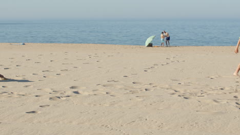 Slow-motion-of-boy-kicking-ball-to-friends-and-falling-on-beach