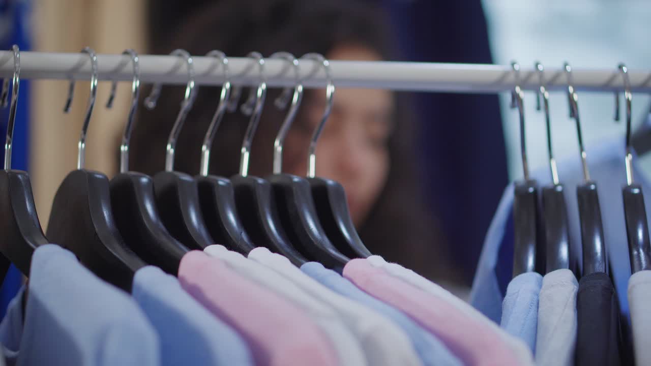 여자 가 랙 에 있는 옷 을 보고 있다
