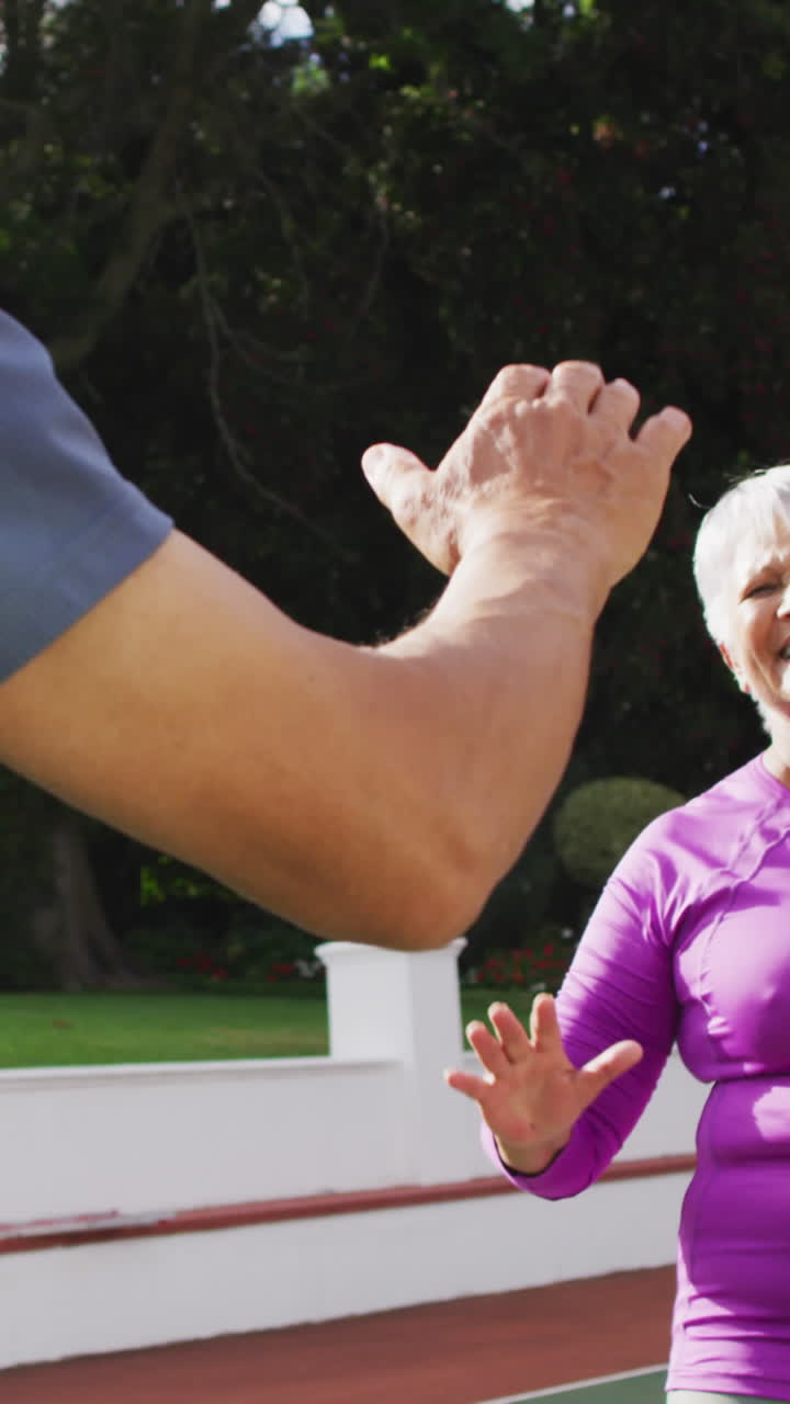 video de una feliz pareja de adultos de dos razas aplaudiendo las manos después del partido en la cancha de tenis