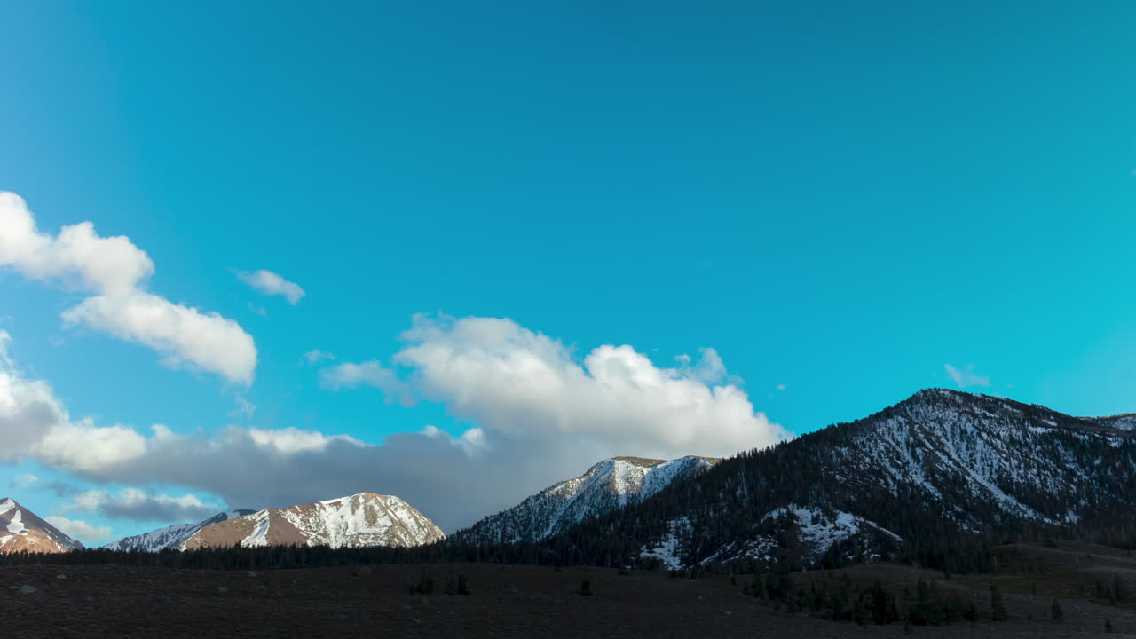 구르는 구름과 푸른 하늘이 있는 눈 덮인 산맥