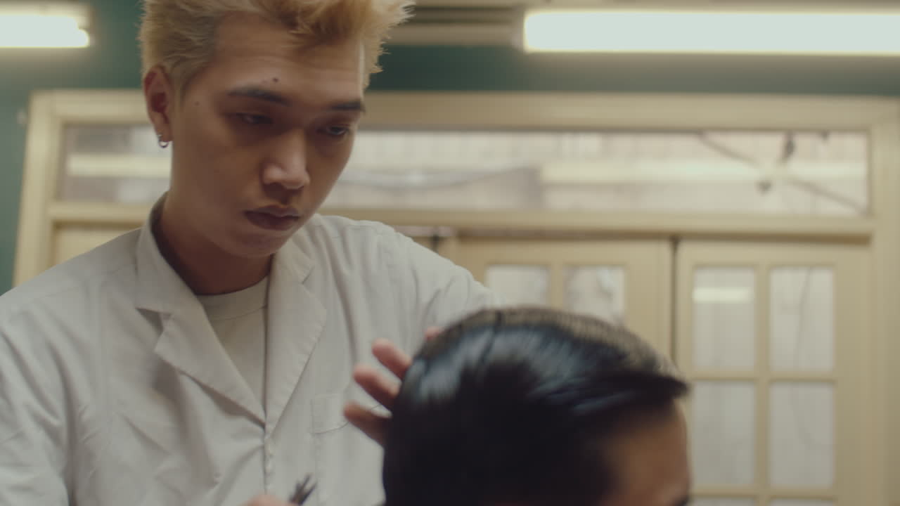 Asian Barber Cutting Hair of Man in Barbershop