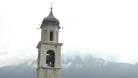 Handheld-shot-of-church-tower-in-a-scenic-location-having-it's-bell-toll-for-serious-reason