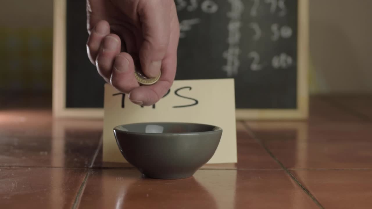 팁 항아리 중간 샷에 동전을 넣는 손