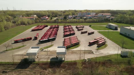 slowly flying over a parking lot for public transportation buses. one red  bus is driving away. industrial background on transportation theme.