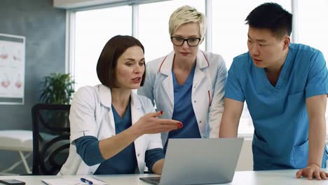 diverse medical team collaborating on a patient diagnosis using a laptop