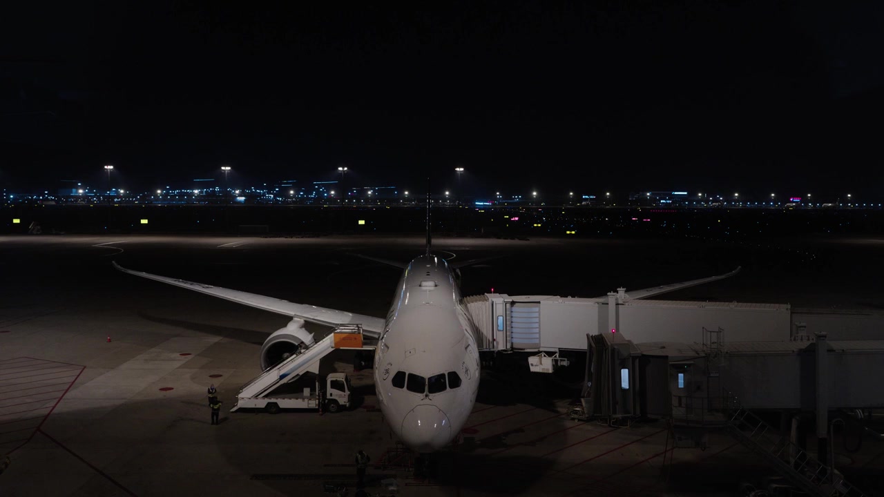 Aereo commerciale attraccato al finger sul piazzale dell'aeroporto di notte con le luci della città sullo sfondo, Cina