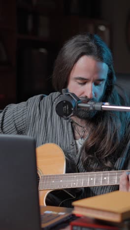 musician playing acoustic guitar and singing into a microphone
