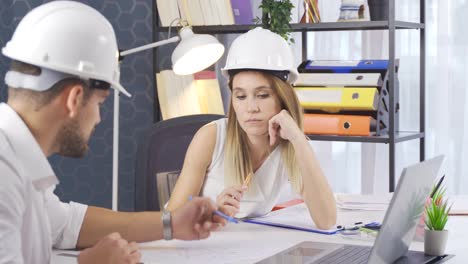 dos arquitectos hablando de un proyecto de dibujo en una oficina de arquitectura.