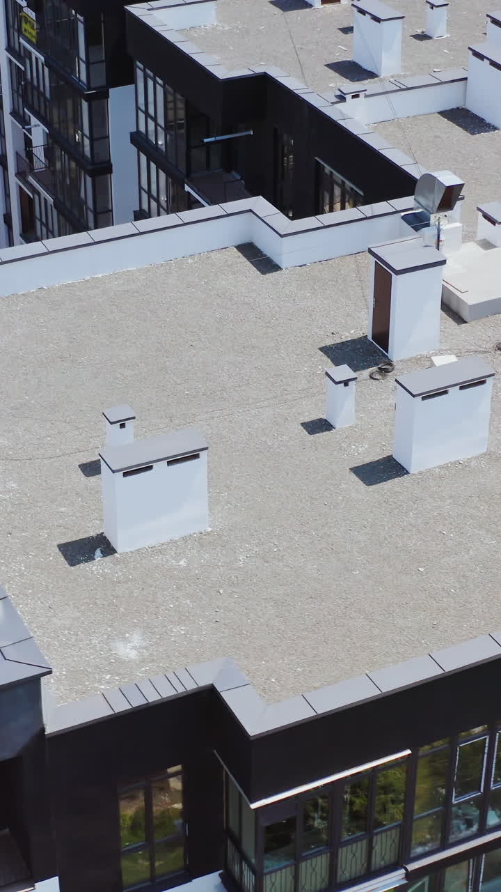 Roofs of a modern multi-storey complex. High apartment buildings in new district in the city. Top aerial view. Vertical video