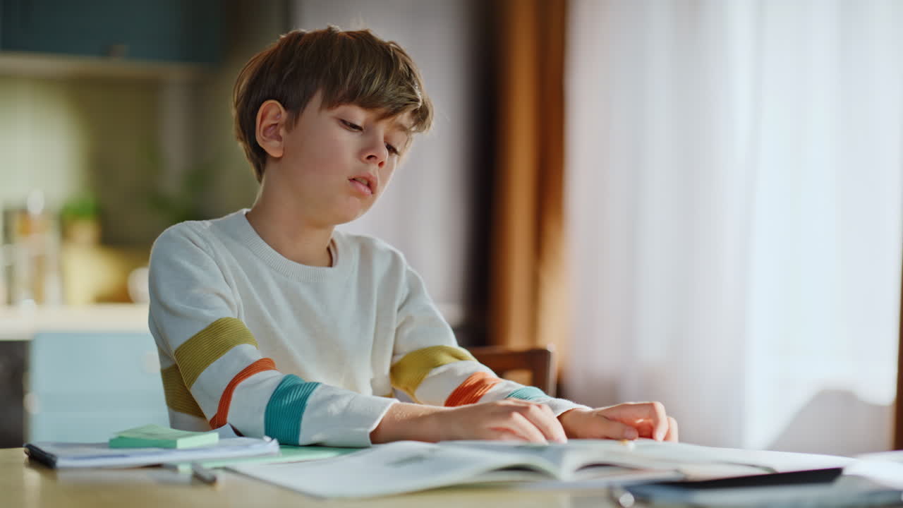 Alunno triste e stanco della didattica a distanza seduto alla scrivania di casa in primo piano. Ragazzo assonnato che studia.