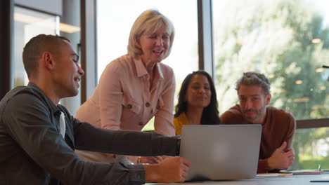 Multi-Cultural-Business-Team-Meeting-Around-Laptop-In-Modern-Office