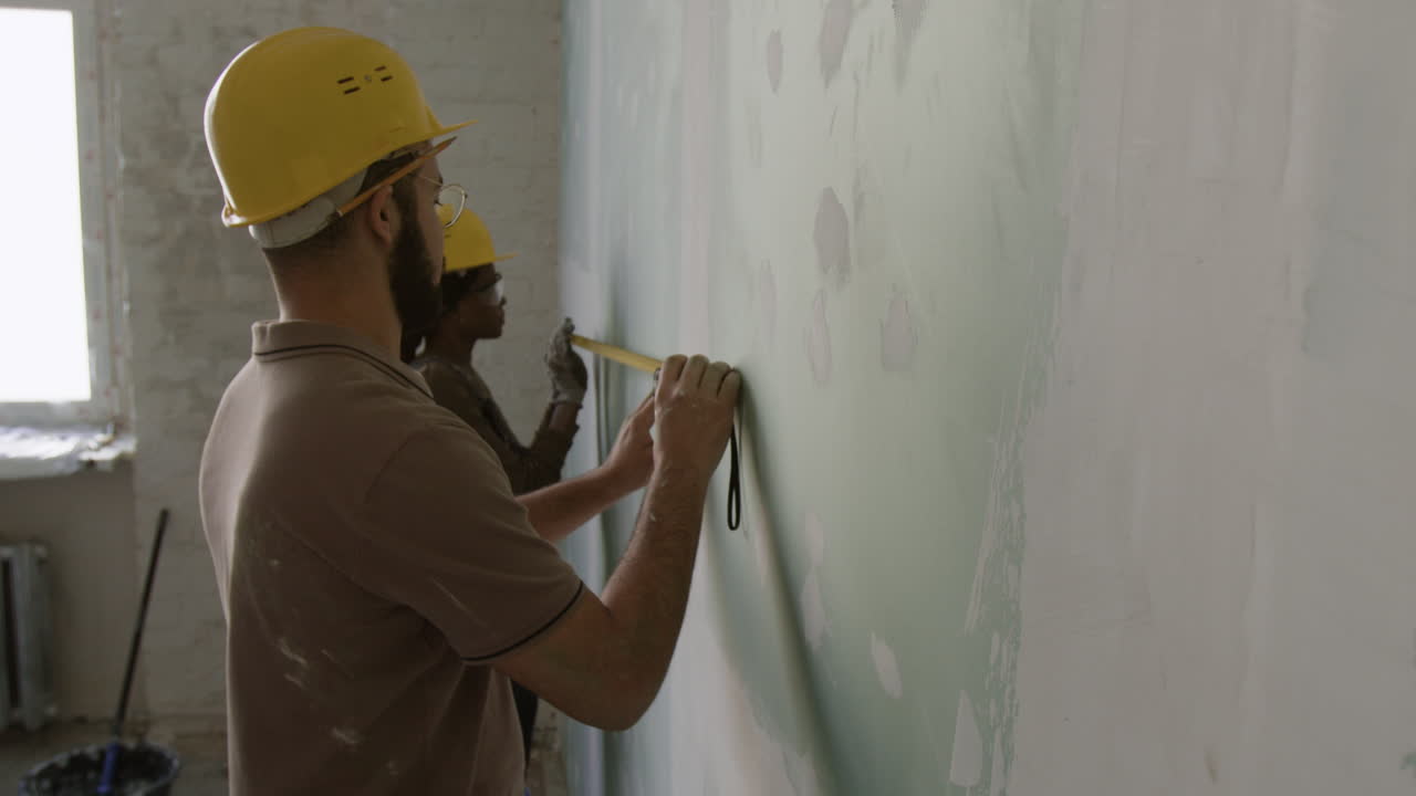Construction workers measuring a wall during renovation