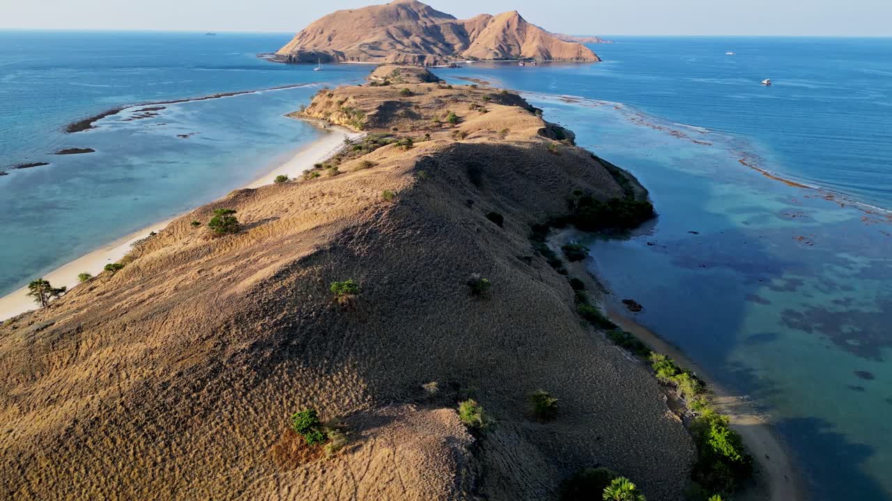 Drone video revealing a long narrow island surrounded by shallow coral reefs