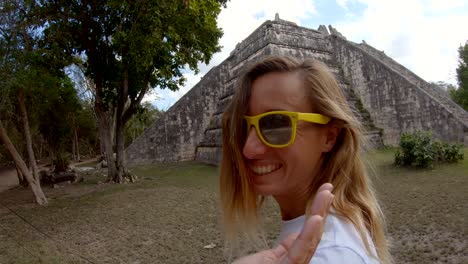 young woman walking around ancient mayan temple in mexico exploring and discovering cultures. girl traveling in mexico, central america. looking at camera