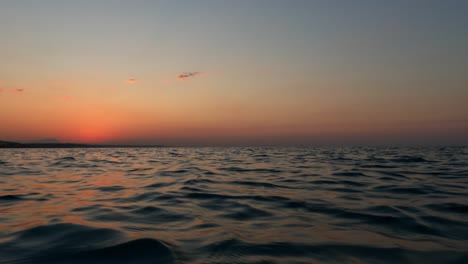 Hermoso-Punto-De-Vista-De-ángulo-Bajo-A-Nivel-Del-Mar-Desde-Un-Velero-Navegando-En-La-Superficie-Del-Agua-Del-Mar-Al-Atardecer