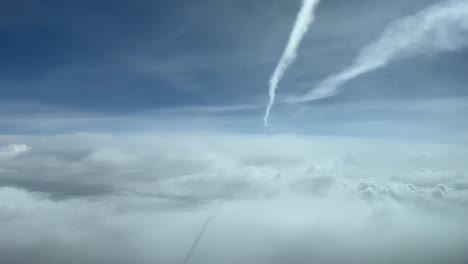 vista del cielo desde la cabina de un jet durante el vuelo sobrevolando las nubes y debajo de otra estela de jet