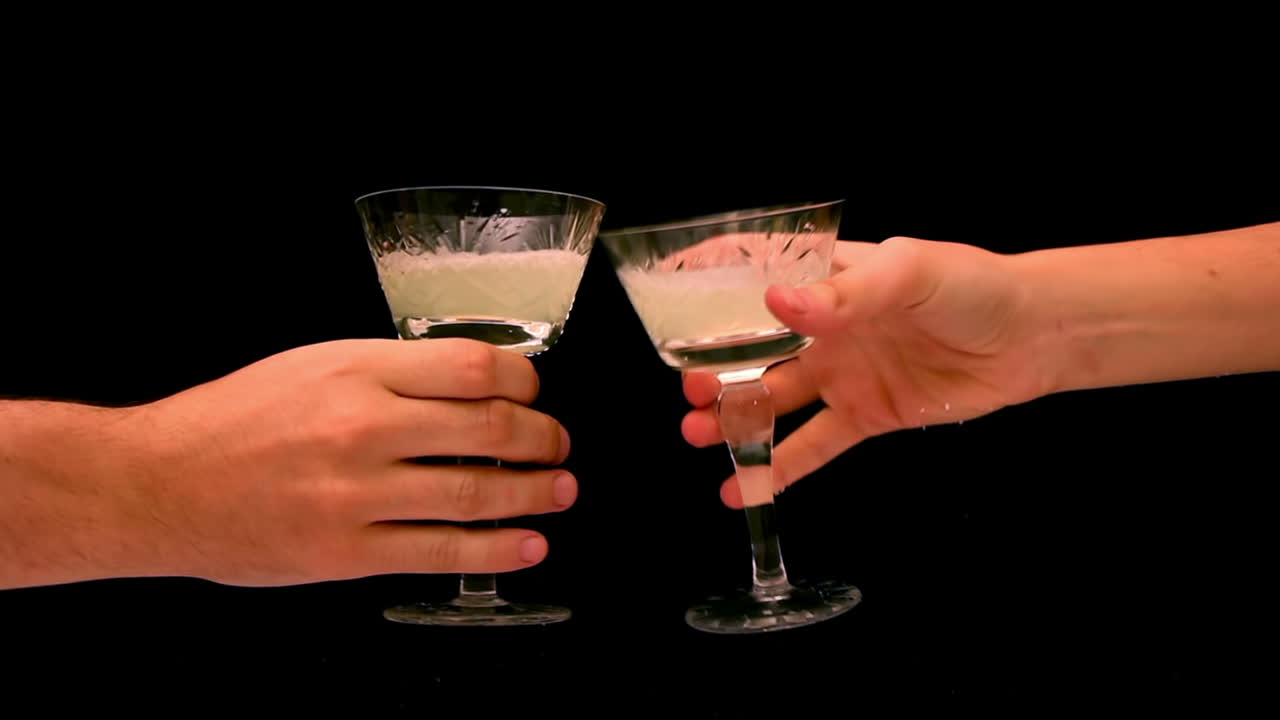 To hænder skåler med cocktailglas på sort baggrund