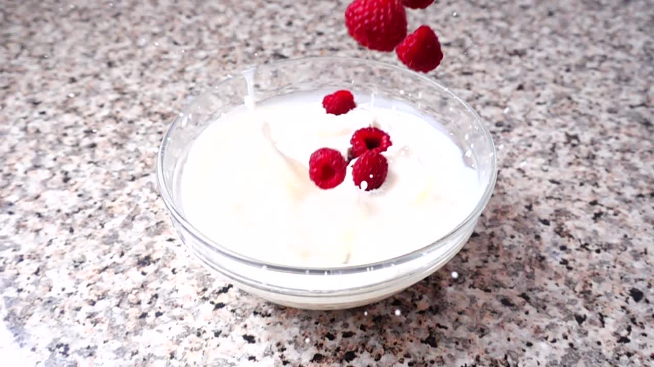 Queda de framboesa no leite. Câmera lenta. Filmagem de frutas. Câmera lenta.