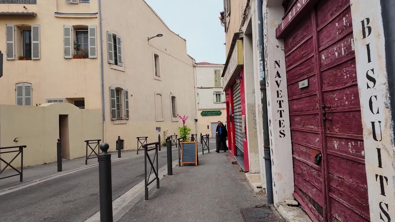 Tracking shot moves through a quiet narrow street with colorful pastel French architecture