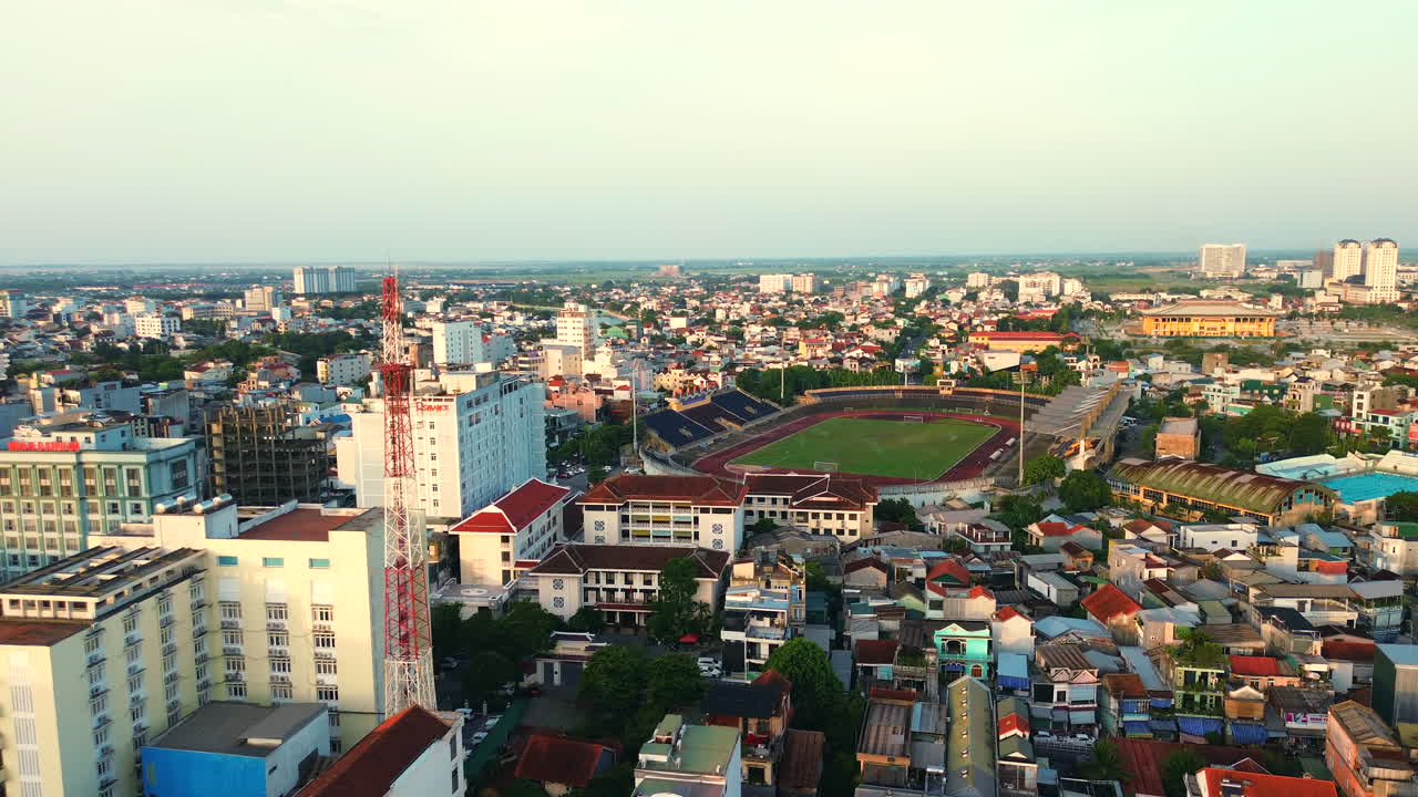 Ảnh toàn cảnh từ trên không trung về trung tâm thành phố Huế có Sân vận động Tự Do, các khách sạn cao tầng và khu dân cư dưới bầu trời buổi hoàng hôn ấm áp.