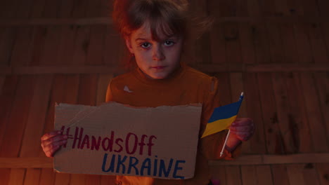 Afraid-Ukrainian-girl-with-inscription-massage-Hands-Off-Ukraine-hiding-from-bombing-attack-at-home