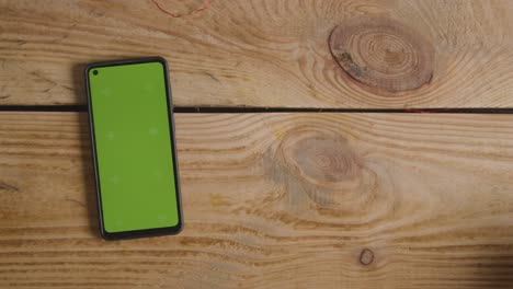 overhead shot of romantic valentines present in gift wrapped box next to green screen mobile phone