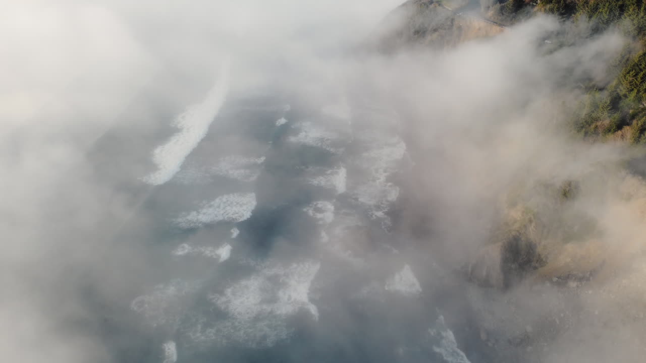 un dron de olas rompiendo en la niebla y la selva tropical costera en la costa de oregon, un océano cambiante y relajante