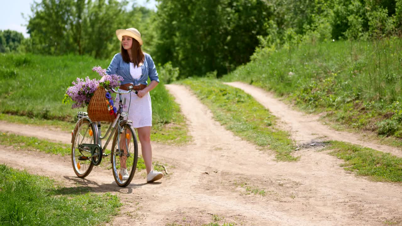 자연에서 여행하는 자전거에 모자를 입은 매력적인 소녀